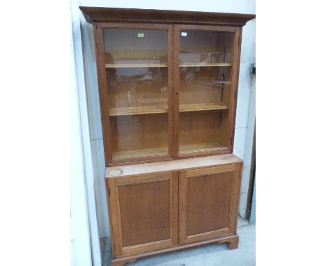 An early 20th century light oak bookcase, enclosed by a pair of glazed doors over a pair of panel doors on bracket feet. 42' 