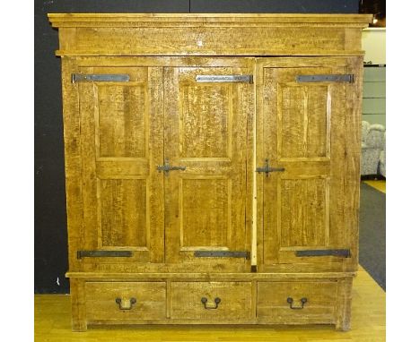 A modern oak and pine lined wardrobe, with three doors above three drawers, decorated with metal strapwork, hinges and handle