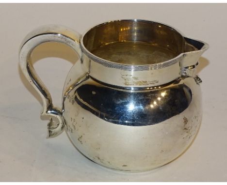 A silver jug, hallmarks for London 1928 Edward Barnard & Sons Ltd, of plain design with ribbed rim, foliate relief under spou