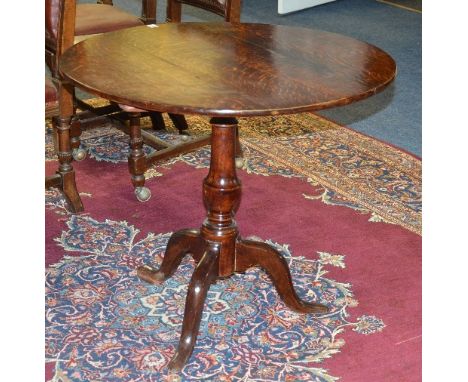 A George III oak snap top supper table, the circular top raised on turned column and tripod supports, 72cm high x 81cm wide