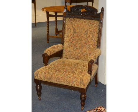 A Victorian mahogany framed parlour armchair, upholstered in later beige floral fabric, raised on turned supports with cerami