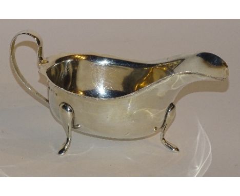 A silver sauce boat, hallmarks for Sheffield 1940 EV, of plain design with scalloped rim raised on plain tripod supports, 8cm