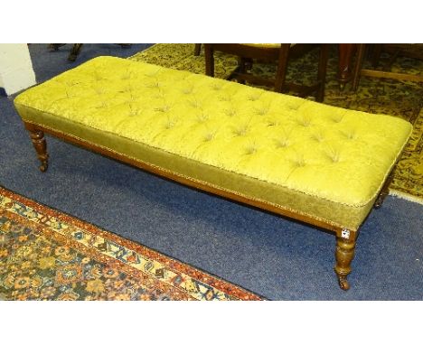 A mahogany fender stool circa late 19th/early 20th century, upholstered in later gold coloured floral fabric, raised on turne