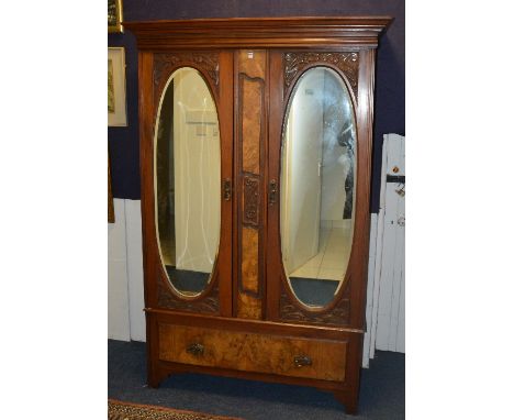 A late Victorian walnut wardrobe, with moulded cornice above two mirrored doors and large drawers, 202cm high x 131cm wide x 