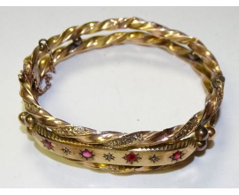 A Victorian yellow metal ruby and diamond bangle, set with four rubies interspersed by three milidiamonds, set in twisted fol