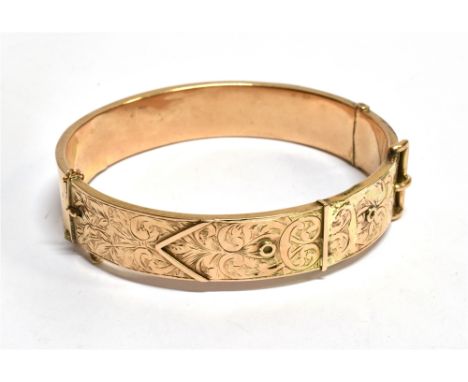 A HALLMARKED 9CT GOLD HINGED BANGLE in the form of a belt and buckle, engraved scroll decoration to front of hollow construct
