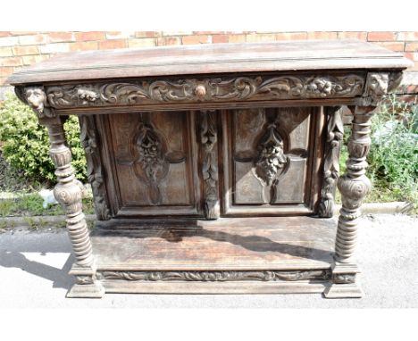 A CARVED OAK BUFFET  with frieze drawer flanked by lion masks above carved pilasters and pot shelf base, 142cm wide