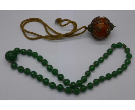 An amber coloured bead pendant and a jade bead necklace