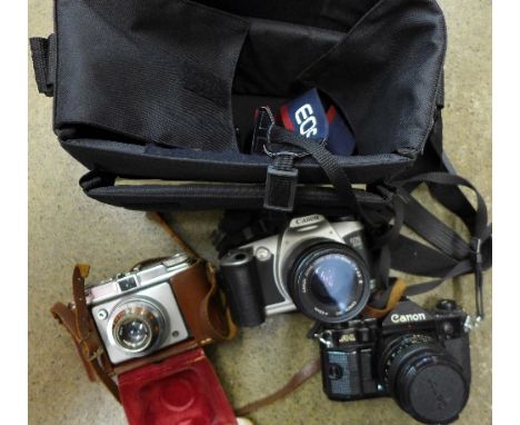 A Canon A-1 camera, a Canon EOS camera and one other