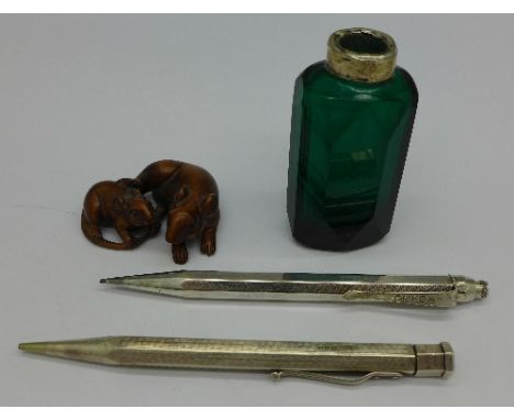 A silver Yard-O-Led pencil, one other pencil marked Omega, a modern netsuke and a green glass bottle lacking stopper