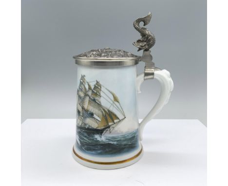 A ceramic drinking vessel decorated with a transfer of two large ships sailing the ocean embellished with gold and a hinged h