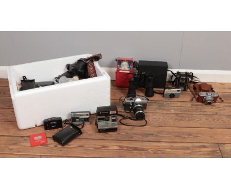 A box of assorted film cameras and equipment. To include a Polaroid 600 Land Camera, Praktica SLR camera and Zenith Binocular