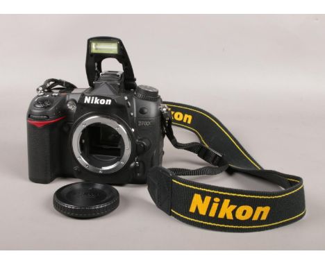 A Nikon D7000 SLR camera body with battery, lens protector and strap. Serial number 6056969.  Flash will not close.