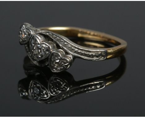 An 18ct gold and platinum three stone diamond ring. The stones in three heart shaped settings. Size I 1/2. 2.59g.  