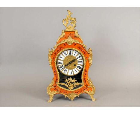 A French Louis XV style mantle clock, the dial with cushion enamels populated with black Roman numerals, beneath a glazed pan