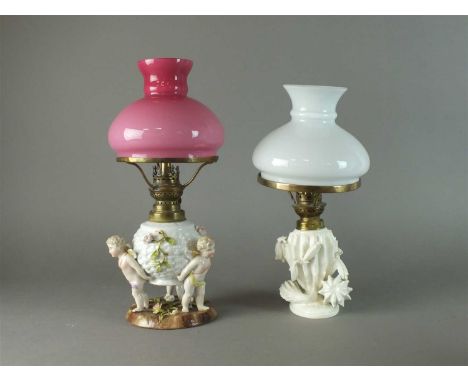 A Plaue porcelain figural oil lamp with central white reservoir applied with pink roses and flanked by three winged putti, on