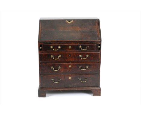 A rustic George III country oak bureau, with a fitted interior and four long drawers fitted with brass handles, raised on bra