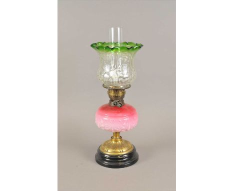 A Victorian electrified oil lamp, with an embossed brass column decorated with stylised floral motifs below a cranberry tinte