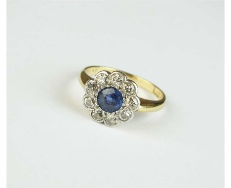 An early 20th century sapphire and diamond floral cluster ring, designed as a central round mixed cut sapphire claw set withi