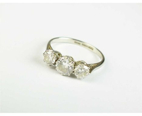 A graduated three stone diamond ring, the brilliant cut diamonds claw set in white metal, the white metal shank stamped '18ct