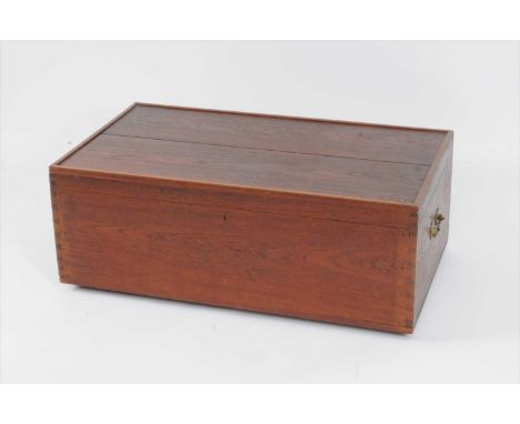 A 20th century teak steamer / luggage trunk, with a hinged cover opening to reveal a vacant interior, flanked by heavy brass 