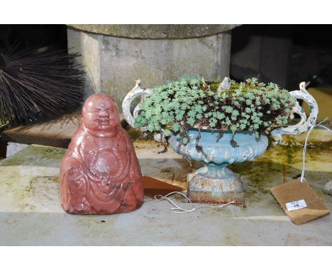 A cast iron planter and a glazed Buddha.