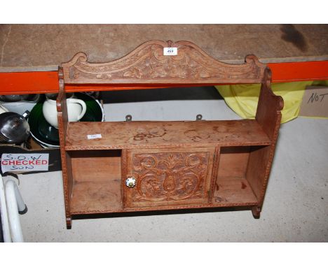 A carved wall hanging kitchen shelf.