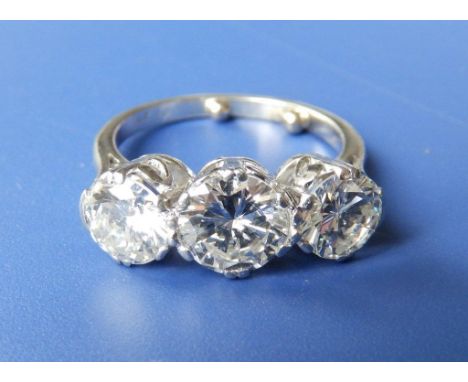 A three stone diamond ring, the central brilliant cut stone weighing approximately one carat, flanked by two stones each weig