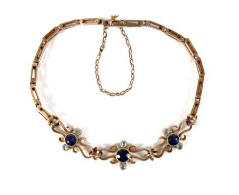 A 9ct yellow gold and sapphire bracelet, with three scrolling panels, each set with a circular faceted cut sapphire, each 4.0