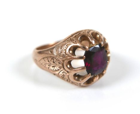 A 9ct gold and ruby coloured stone ring, the cushion cut stone 5 by 6.5mm, engraved scrolling leaves to shoulders, size L, 4.