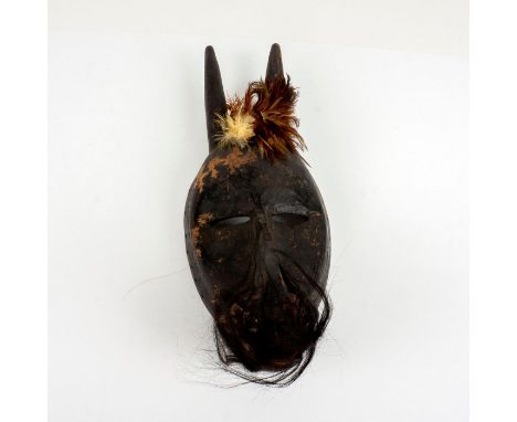 Black wood carved mask in the shape of a donkey decorated with horse hair. Masks are used in celebrations or ceremonies. Mask