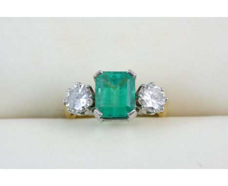 AN EMERALD AND DIAMOND THREE STONE RING the step-cut emerald is set with two circular-cut diamonds weighing approximately 0.6