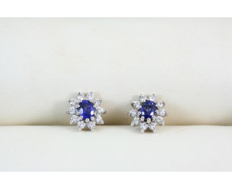 A PAIR OF SAPPHIRE AND DIAMOND CLUSTER STUD EARRINGS the oval-shaped sapphires are set within a surround of ten circular-cut 