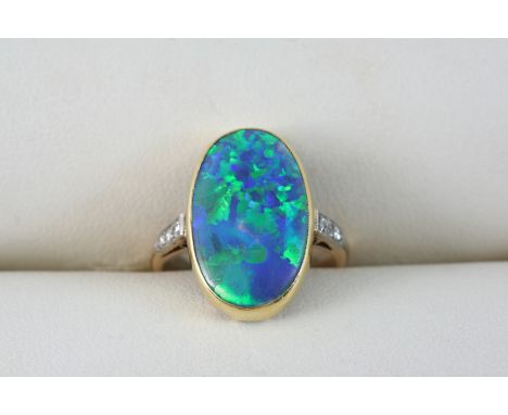 A BLACK OPAL AND DIAMOND RING the oval-shaped black opal is set with three small diamonds to each shoulder, in 18ct. gold. Si