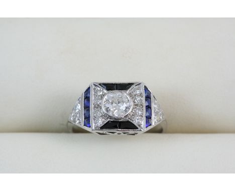 AN ART DECO STYLE DIAMOND, SAPPHIRE AND BLACK ONYX RING centred with a circular-cut diamond within a surround of calibre-cut 