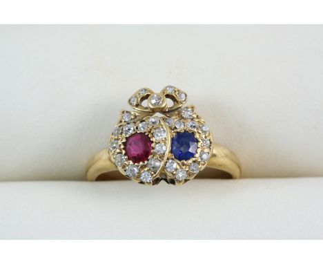 A SAPPHIRE, RUBY AND DIAMOND DOUBLE HEART RING one heart set with an oval-shaped ruby, the other with a sapphire, within a su