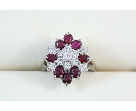 A RUBY AND DIAMOND CLUSTER RING centred with a cluster of seven brilliant-cut diamonds within a surround of eight oval-shaped