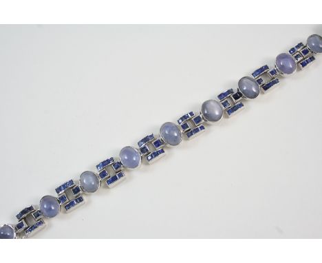 A SAPPHIRE BRACELET formed with nine graduated oval star sapphires, alternately set with white gold links set with calibre-cu