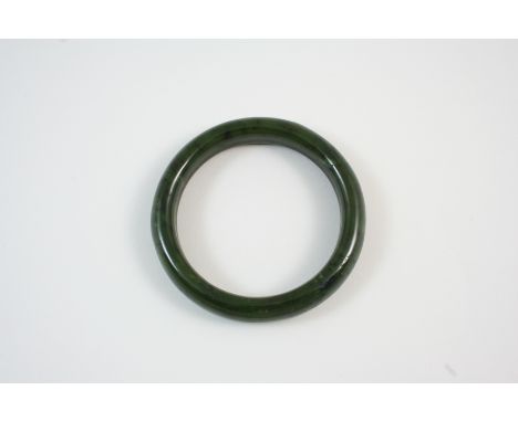 A MOTTLED GREEN JADE BANGLE 8cm. wide.