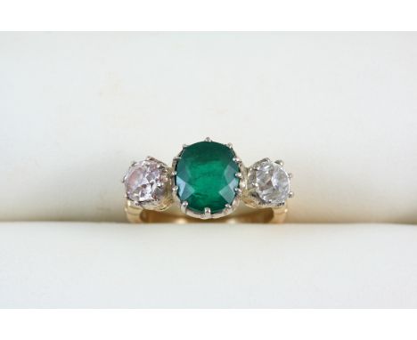 AN EMERALD AND DIAMOND THREE STONE RING the oval-shaped emerald is set with two old brilliant-cut diamonds, in 18ct. gold. Si