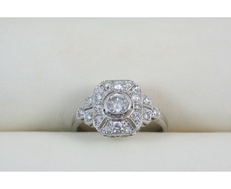 A DIAMOND CLUSTER RING centred with a circular-cut diamond within a surround of circular-cut diamonds in 18ct. white gold. Si