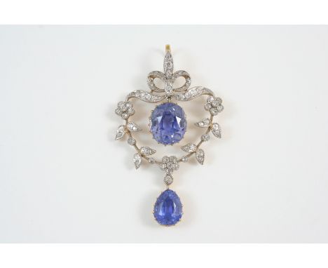 A BELLE EPOQUE SAPPHIRE AND DIAMOND PENDANT the foliate scroll mount is centred with an oval sapphire drop and suspends a pea