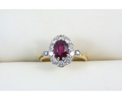 A RUBY AND DIAMOND CLUSTER RING the oval-shaped ruby is set within a surround of circular-cut diamonds, in 18ct. gold. Size L