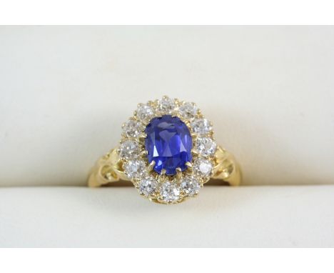 A SAPPHIRE AND DIAMOND CLUSTER RING the oval-shaped sapphire is set within a surround of twelve circular-cut diamonds, in gol