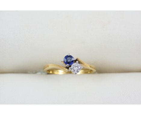 A SAPPHIRE AND DIAMOND CROSS-OVER RING the circular-cut sapphire and diamond are set in 18ct. gold. Size J.