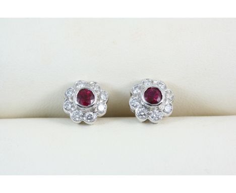 A PAIR OF RUBY AND DIAMOND CLUSTER STUD EARRINGS each set with a circular-cut ruby within a surround of eight circular-cut di