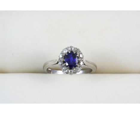 A SAPPHIRE AND DIAMOND CLUSTER RING the oval-shaped sapphire is set within a surround of circular-cut diamonds, in 18ct. whit