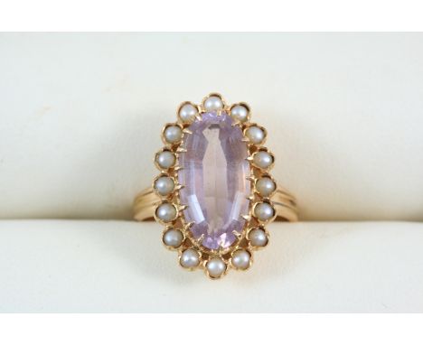 AN AMETHYST AND PEARL CLUSTER RING the oval-shaped amethyst is set within a surround of small pearls, in gold, with French ma