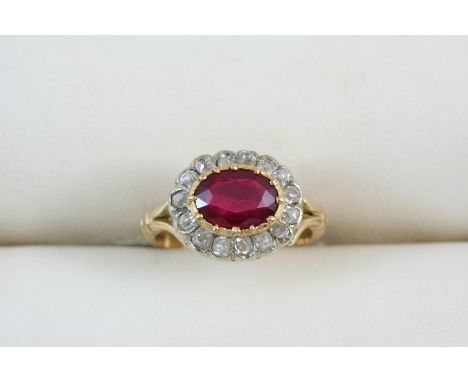 A RUBY AND DIAMOND CLUSTER RING the oval-shaped ruby is set within a surround of fifteen old brilliant-cut diamonds, in 18ct.