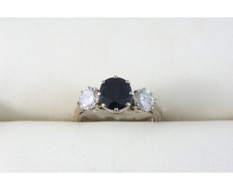 A SAPPHIRE AND DIAMOND THREE STONE RING the oval-shaped sapphire is set with two circular-cut diamonds. Size J.